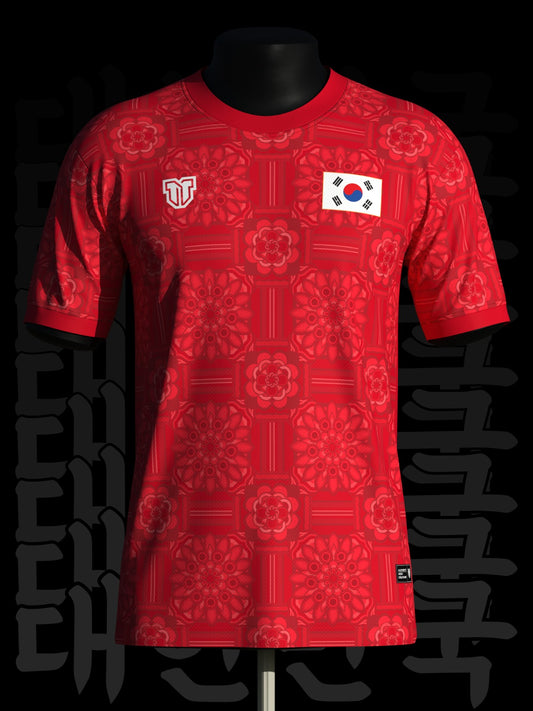 Red sports jersey with a pattern and a flag patch on a black mannequin against a dark background.