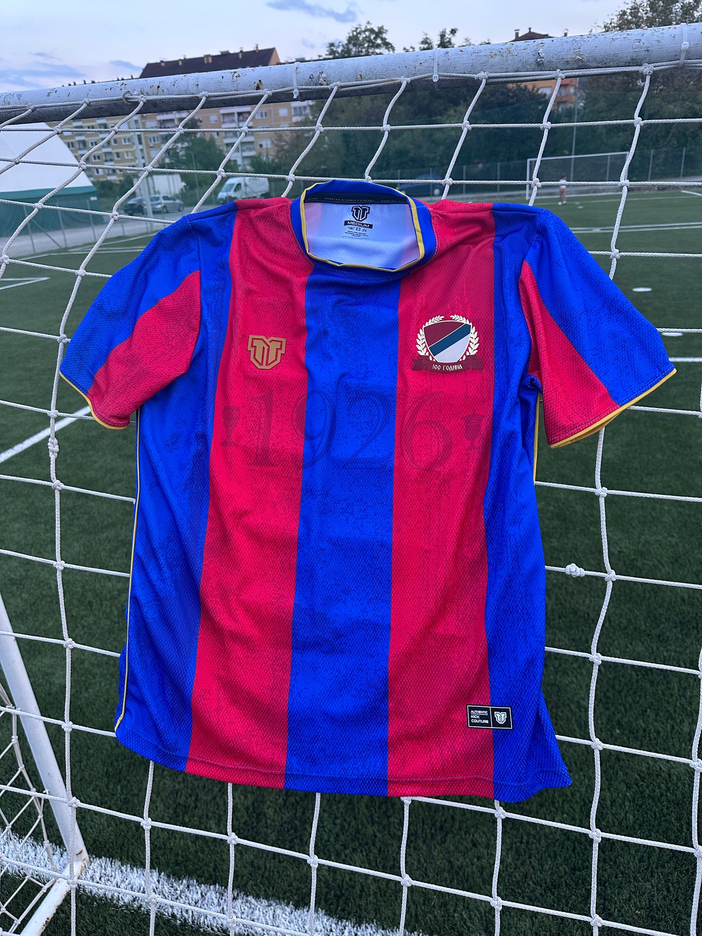Red and blue sports jersey with brand logos on a soccer goal net