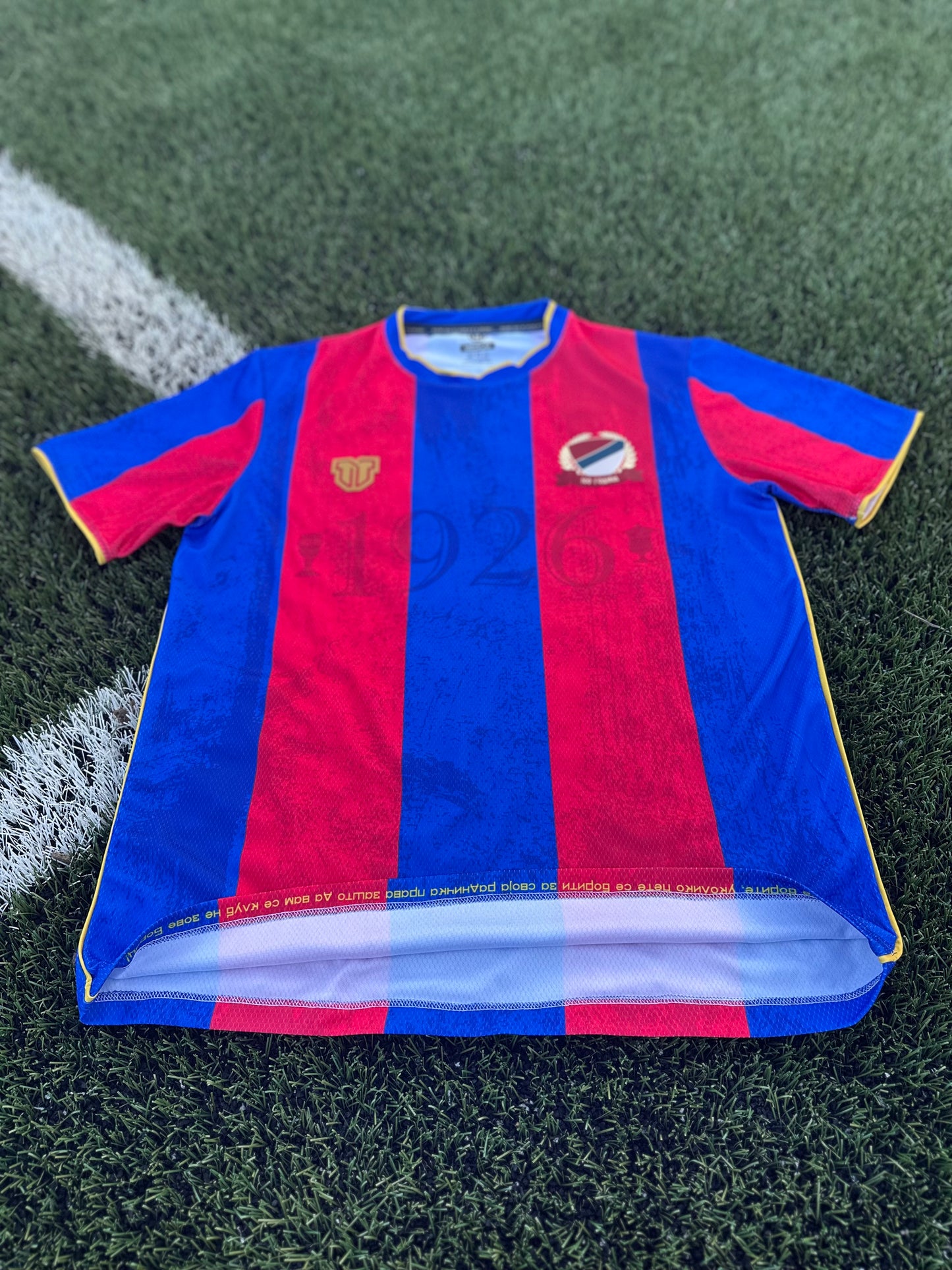 Blue and red striped sports jersey on a grass field